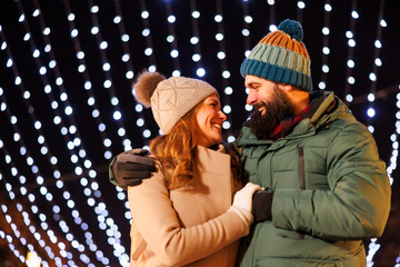 Obraz premium Couple hugging and walking down decorated city streets at Christmas