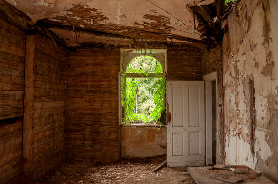 Abandoned overgrown mansion with spiral staircase, old car and ruined interior