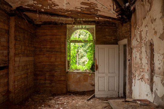 Abandoned overgrown mansion with spiral staircase, old car and ruined interior