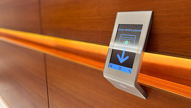 Close-up of a modern card reader terminal mounted on a warm polished wood panel.
