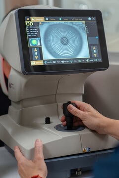 Female optician or optometrist specialist checking vision of a Senior man using examination equipment inside an optometry clinic