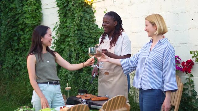 Diverse female friends toasting with wine at a backyard barbecue