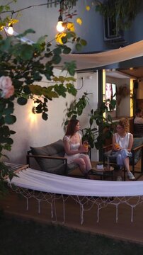 Two female friends drinking cocktails and talking at an outdoor cafe meeting