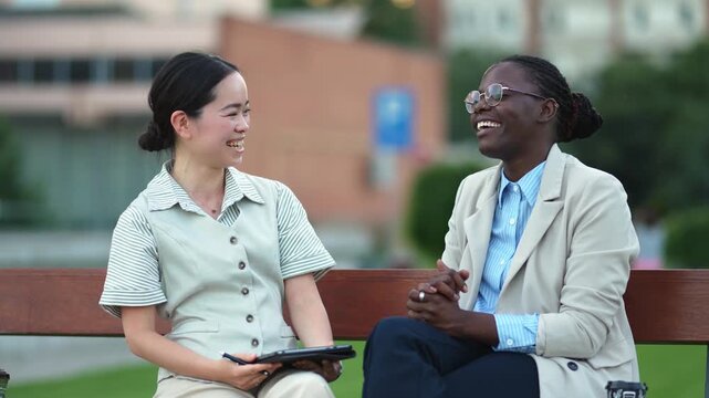 Diverse businesswomen discussing work plans on a bench