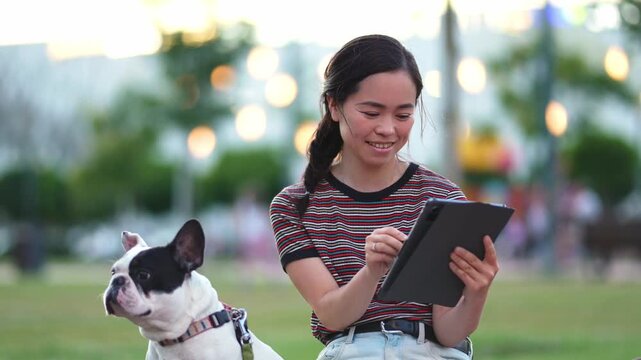 Young japanese woman drawing on a tablet in a park with her dog