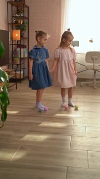 Two little girls in dresses holding hands at home
