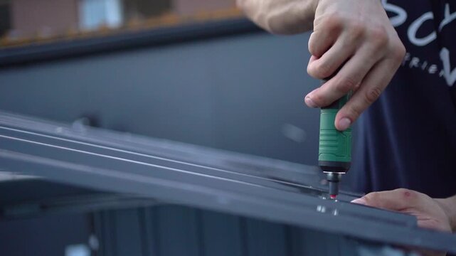 Worker using a power screwdriver on a metal sheet in slow motion