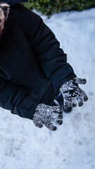 Person wearing black winter coat and snow-covered gloves in the cold outdoors © shine.graphics