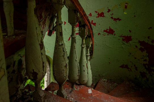 Abandoned overgrown mansion with spiral staircase, old car and ruined interior