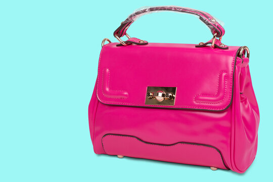 Vibrant magenta pink leather handbag with gold clasp on cyan background with copy space. Stylish womens purse side view