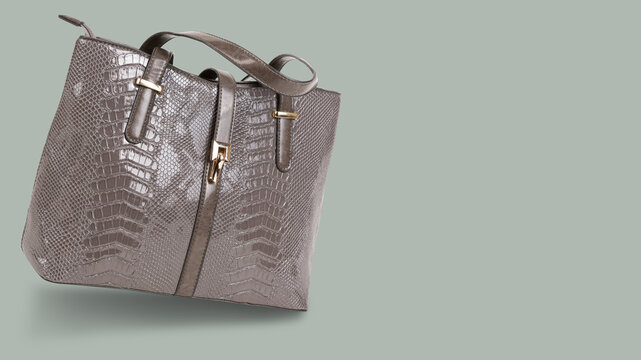 Elegant grey snake skin textured leather tote bag on pastel background with copy space. Womens stylish handbag side view
