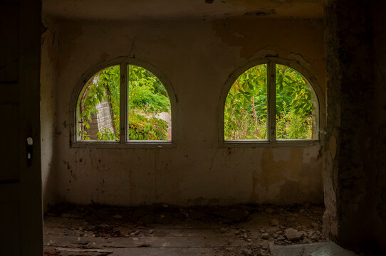 Abandoned overgrown mansion with spiral staircase, old car and ruined interior