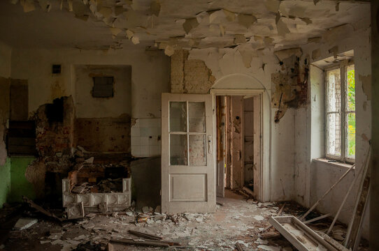 Abandoned overgrown mansion with spiral staircase, old car and ruined interior