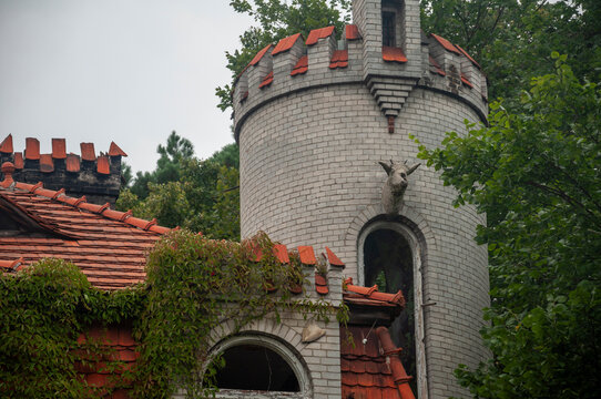 Abandoned overgrown mansion with spiral staircase, old car and ruined interior
