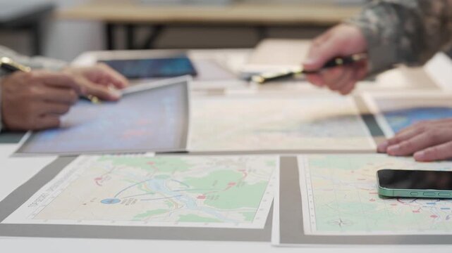 Military officers analyzing tactical map documents and digital tablet in command war room