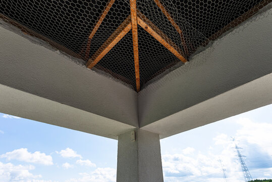 Attic roof with wooden trusses and metal mesh protection