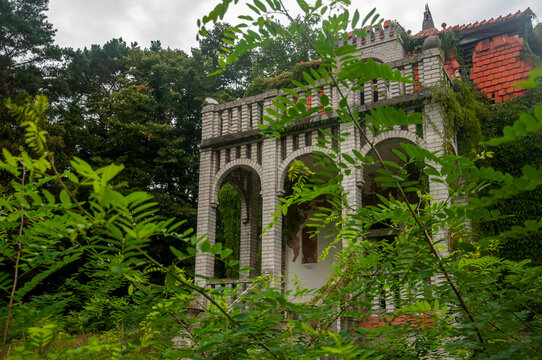 Abandoned overgrown mansion with spiral staircase, old car and ruined interior