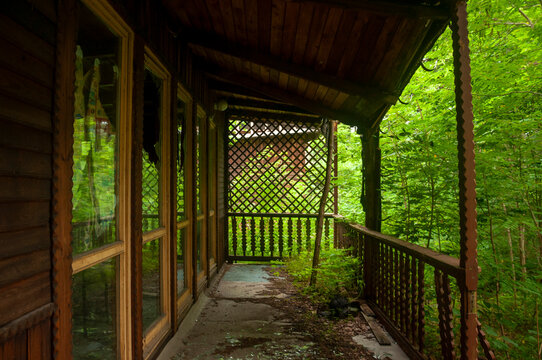 Abandoned overgrown mansion with spiral staircase, old car and ruined interior