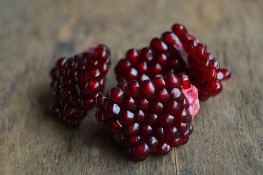 Close up of fresh pomegranate seeds and chunks on a wooden background.