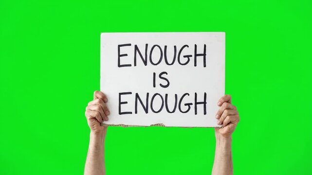 Hands holding a banner sign with the text enough is enough on a green screen chroma key background