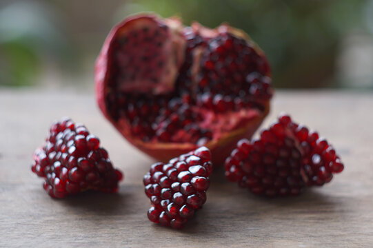 Ripe opened pomegranate fruit with seeds on dark wooden table.