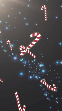 Multiple candy cane icons falling against blue spots of light on black background