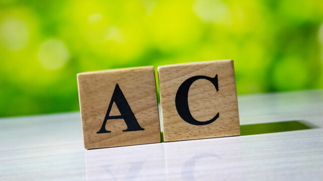 Two wooden cubes showing letters A and C on bright green bokeh background for academic or professional branding.
