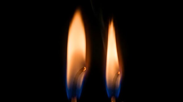 Two burning matchstick flames on black background