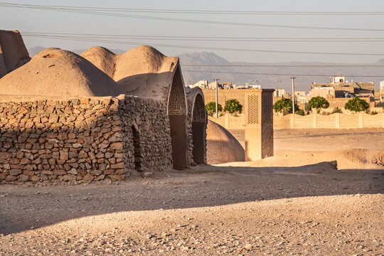 Adobe domes and stone walls at the Towers of Silence (Dakhma) near Yazd, Iran, showing Zoroastrian heritage architecture in an arid desert setting, with mountains in the distance. near the desert city