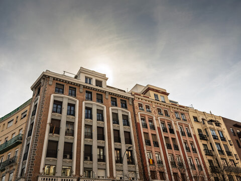 Residential building facades in the city center show multi-story apartments in Madrid, Spain, decorative architectural details typical of dense urban housing and central real estate.