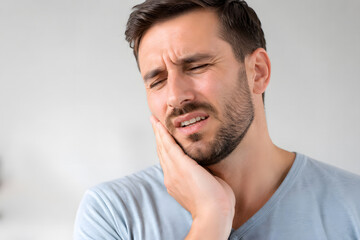 Fototapeta premium Man experiencing facial discomfort clutching his jaw in a studio portrait ache affliction anatomy beard