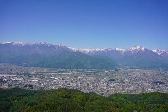 北アルプス　鷹狩山から望む残雪の北アルプスと新緑の大町市街	