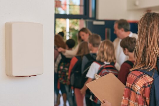 Fire alarm on a smooth white wall in a school corridor with students and adults during an orderly safety drill for emergency education