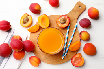 Apricot juice in glass, fresh fruits and drinking straws on white marble table, flat lay © New Africa