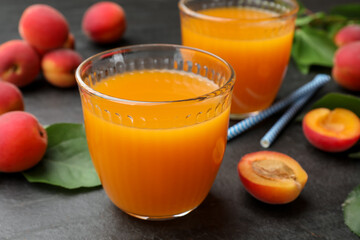 Apricot juice in glasses, fresh fruits and drinking straws on black table, closeup © New Africa