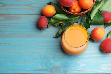 Apricot juice in glass, fresh fruits and leaves on light blue wooden table, above view. Space for text © New Africa