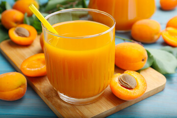 Apricot juice in glass and fresh fruits on light blue wooden table, closeup © New Africa