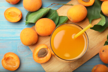Apricot juice in glass, fresh fruits and leaves on light blue wooden table, flat lay © New Africa