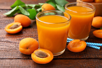 Apricot juice in glasses, fresh fruits and drinking straws on wooden table, closeup © New Africa
