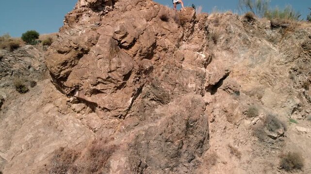 Woman standing on rocky cliff edge embracing freedom and self discovery on a sunlit arid landscape, radiating confidence and the spirit of outdoor adventure for travel and lifestyle campaigns