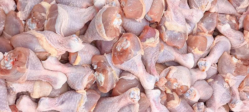 Large quantities of raw chicken legs with the skin still attached. These fresh chicken legs are prepared for wholesale or retail sale.