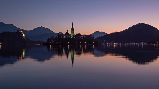 Night to day hyper lapse Bled Island (Blejski otok) with pilgrimage church of the Assumption of Mary and Bled castle on Lake Bled, Slovenia