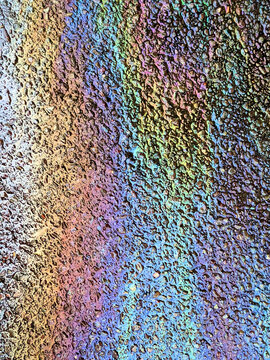 A leaked Car Oil Petrol in The Rain on a Tarmac Road Metallic Rainbow Gasoline