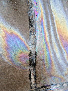 A leaked Car Oil Petrol in The Rain on a Tarmac Road Metallic Rainbow Gasoline