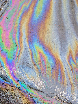 A leaked Car Oil Petrol in The Rain on a Tarmac Road Metallic Rainbow Gasoline