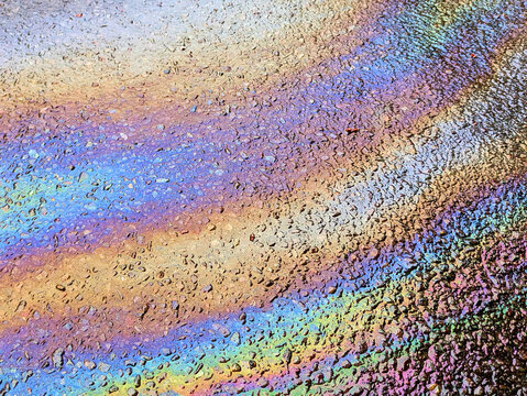A leaked Car Oil Petrol in The Rain on a Tarmac Road Metallic Rainbow Gasoline