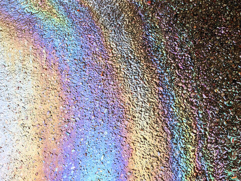 A leaked Car Oil Petrol in The Rain on a Tarmac Road Metallic Rainbow Gasoline