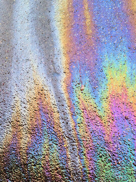 A leaked Car Oil Petrol in The Rain on a Tarmac Road Metallic Rainbow Gasoline
