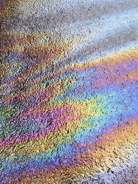 A leaked Car Oil Petrol in The Rain on a Tarmac Road Metallic Rainbow Gasoline