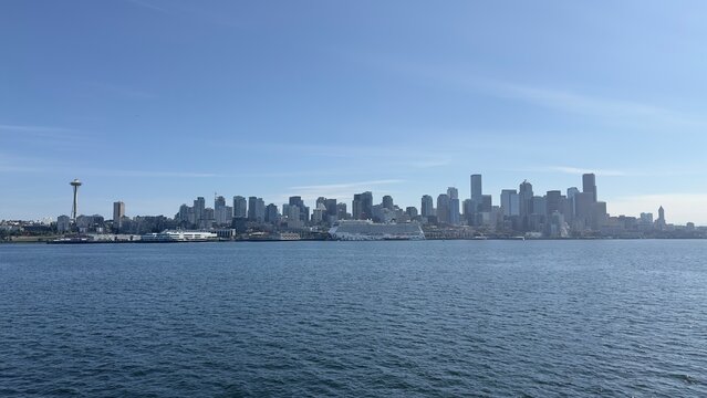 Seattle&rsquo;s waterfront in daylight, with Elliott Bay, bustling piers, and the city skyline stretching along the shore.